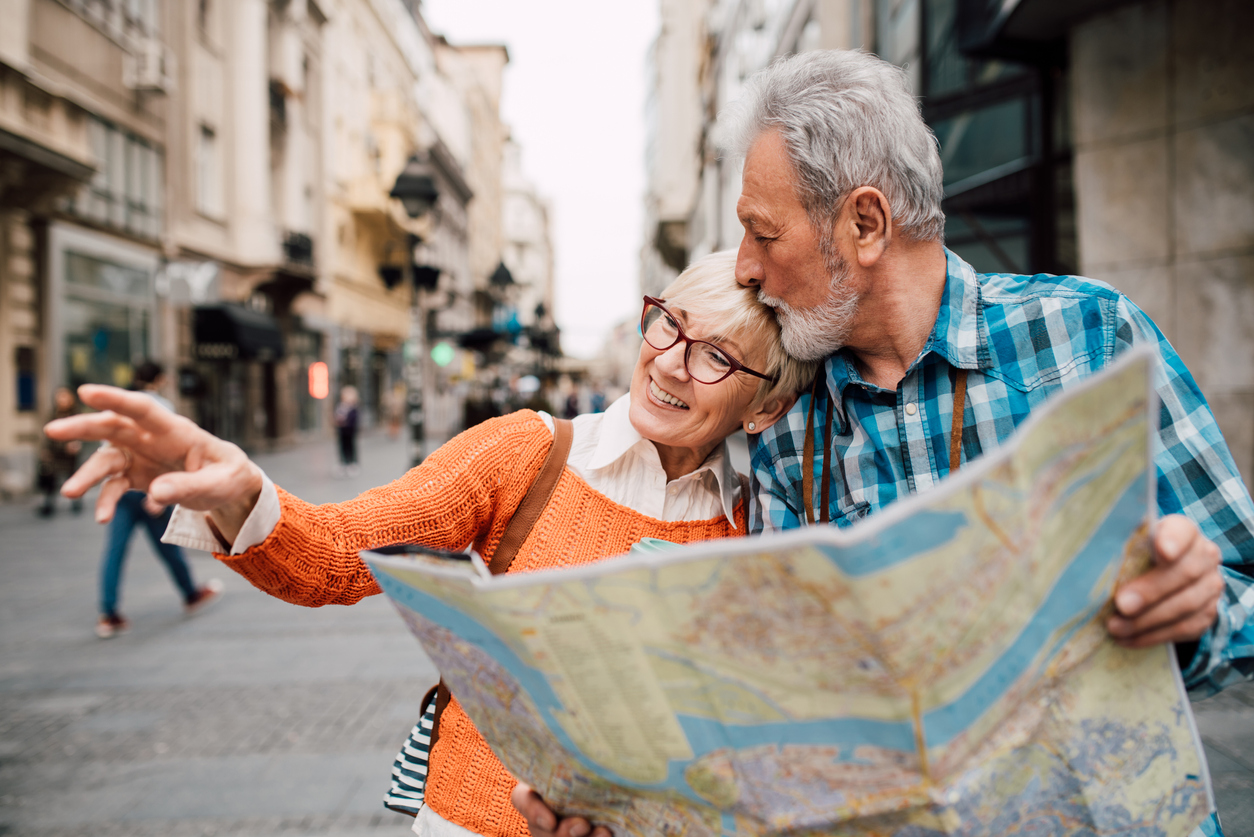 Elderly tourist couple embracing, holding the map and kissing