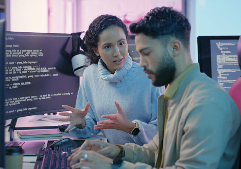 Computer, woman programmer and man training for coding, cyber security or software on computer. Female IT specialist, male coder or talking to connect internet, information update and cloud computing